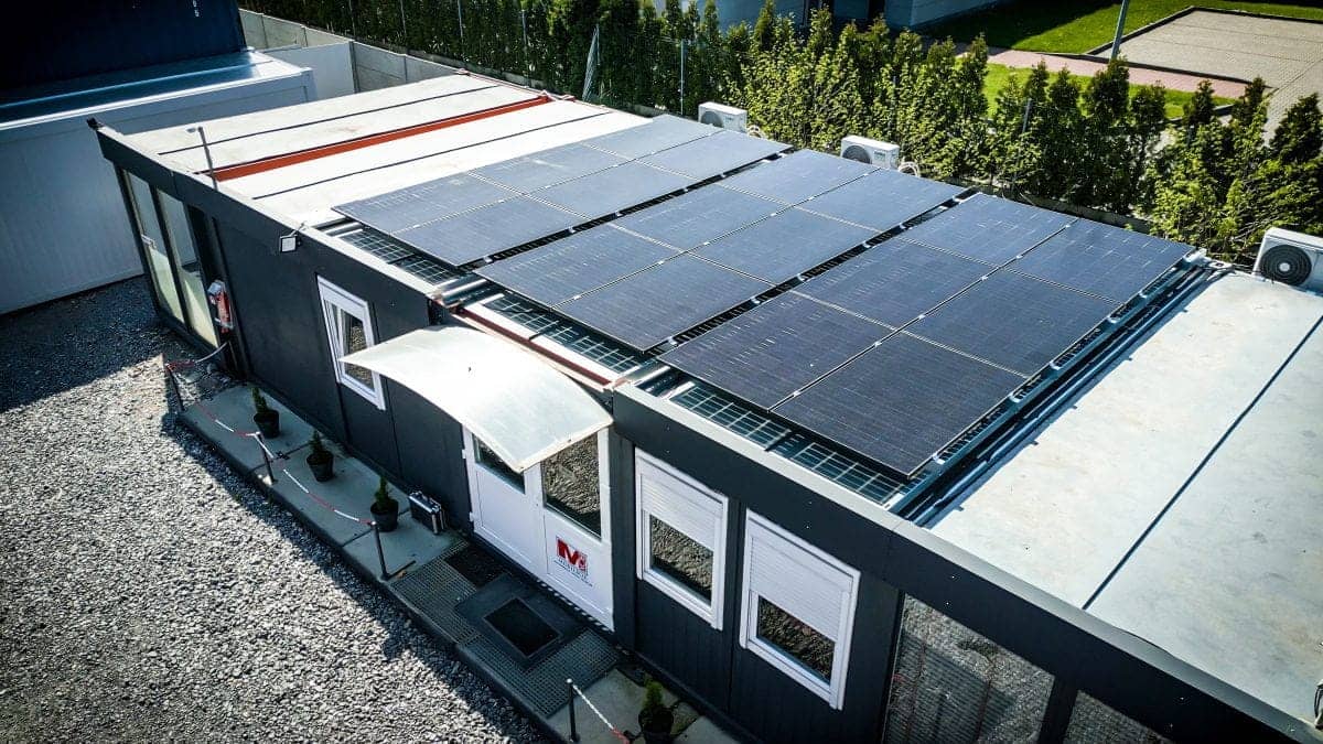 Aerial view of a single-story building with a large array of solar panels on the flat roof.
