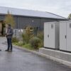 Illustration d’une batterie de stockage devant une entreprise équipée de panneaux solaires
