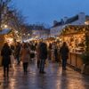 Illustration d’un marché de Noël au crépuscule avec chalets éclairés et visiteurs