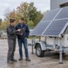 Illustration de deux professionnels étudiant un projet d’équipement à côté d’une remorque solaire et d’une tour d’éclairage