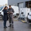 Une responsable et un technicien préparent la recharge temporaire d’utilitaires électriques dans un dépôt — illustration